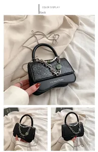 Detail of black crossbody bag with pearl chain, jade stone charm and printed text