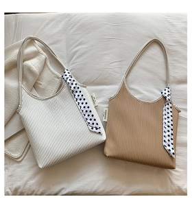 Detailed shot of pleated fabric shoulder bags in white and camel with polka dot scarves