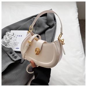 Detail of cream crescent leather bag with golden ring clasp and adjustable strap