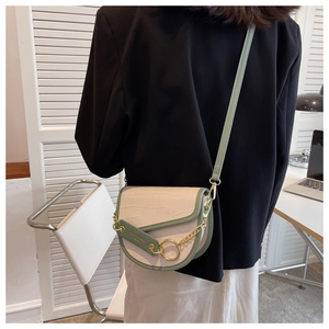 Close-up of contrast color saddle bag with crocodile texture and gold chain strap