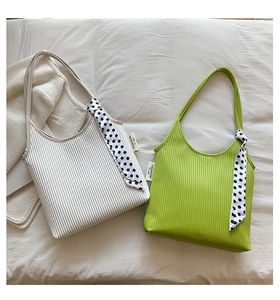Detail of pleated shoulder bags in cream and avocado green with polka dot silk scarves