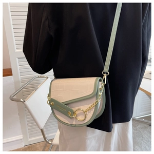 Detail of sage green trim and gold chain on embossed faux leather saddle bag