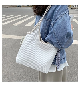 Detail of white pleated tote bag featuring polka dot scarf and fashion textile label