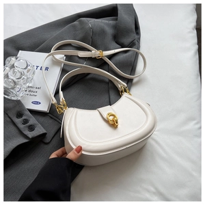 Close-up of a white crescent crossbody bag with gold hardware on an aesthetic background