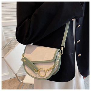 Detail of contrast color saddle bag with crocodile texture and gold chain on black blazer