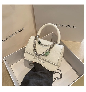 Detailed shot of white pleated crossbody bag with chunky gold chain and pearl charms
