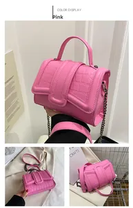 Détail du sac à main rose texture crocodile avec bandoulière chaîne et poignée