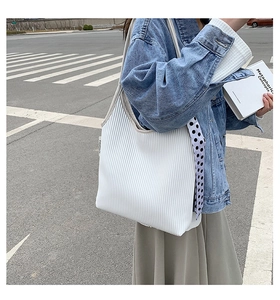Detail of white pleated tote bag with polka dot silk ribbon and fashion tag