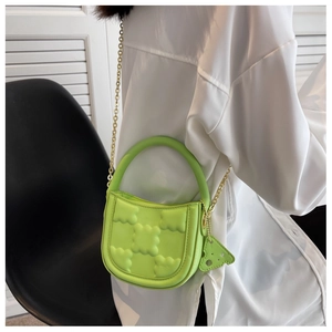 Detail of green biscuit textured crossbody bag with gold chain and cheese charm
