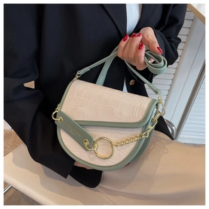 Detail of pink croc-textured saddle bag with green leather trim and gold ring hardware