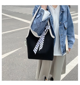 Detail of a ruched black and white shoulder bag with a polka dot scarf accessory