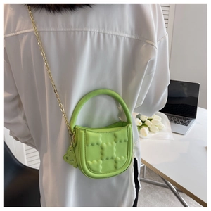 Detail of lime green cookie shaped crossbody bag with gold chain strap on office desk