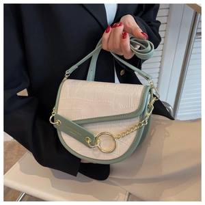 Detail of mint green saddle bag with crocodile texture and gold chain hardware
