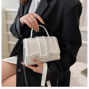 Détail d'un sac à main blanc motif crocodile avec poignée et bandoulière en chaîne