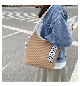 Detail of khaki pleated shoulder bag featuring polka dot silk scarf and fashion tag