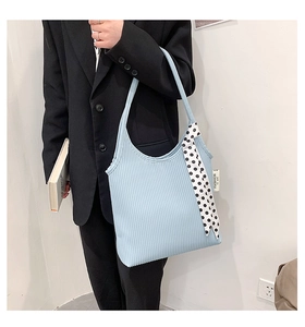 Detail of light blue pleated underarm bag with decorative polka dot ribbon and side label