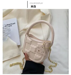 Detail of off-white crossbody bag with bubble texture and cheese charm accessory