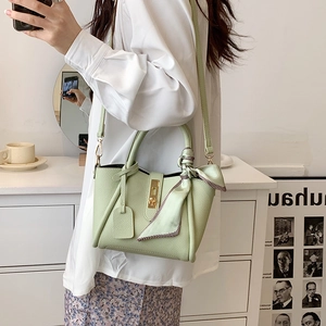 Borsa a secchiello in pelle verde menta con chiusura dorata e foulard in seta in scena