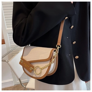 Detail of vintage saddle bag with crocodile texture, gold ring, and contrast trim