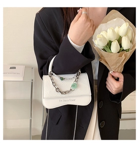 Detail of white wrinkled faux leather bag with chain strap and I'm like a flower print