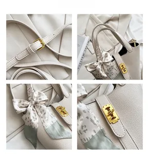 Dettaglio borsa in pelle beige con finiture dorate e foulard decorativo floreale