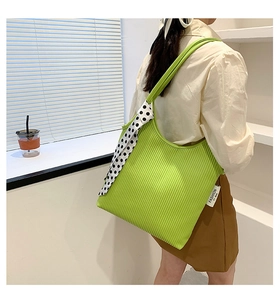 Green ruched shoulder bag with polka dot ribbon accent shown on model in bright setting