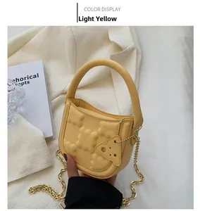 Close-up of light yellow biscuit bag with embossed texture and gold chain strap detail