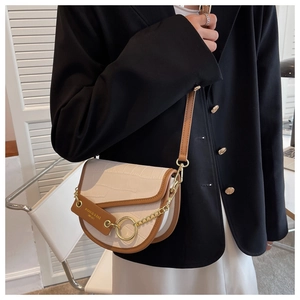 Detail of white crocodile texture saddle bag with gold ring and brown contrast strap