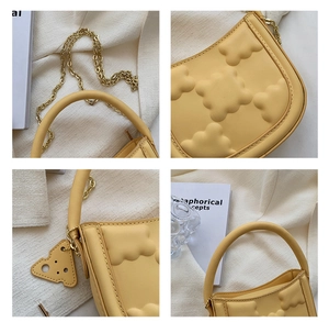 Detail view of yellow biscuit-quilted bag with gold chain and cheese charm pendant