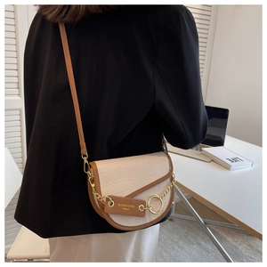 Detail of cream crocodile pattern saddle bag with brown trim and gold ring hardware
