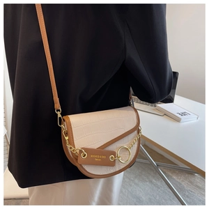Crocodile pattern saddle bag in cream and brown finish worn by model in a modern office