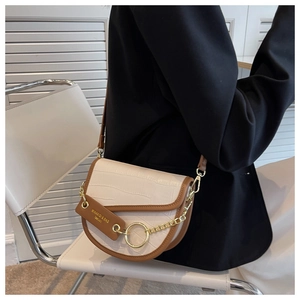 Detail of saddle bag featuring crocodile texture, contrast colors, and golden chain