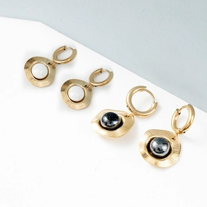 Detail of 18k gold plated hoop earrings featuring embossed discs with black and white stone
