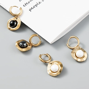 Detail of 18k gold plated hoops with wavy metal discs and black/white stone inlays
