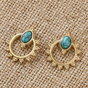 Bohemian gold earrings with oval turquoise stones on rustic jute fabric background