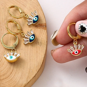 Gros plan de boucles d'oreilles Œil maléfique dorées avec pierres bleues et zircons