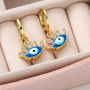 Détail de boucles d'oreilles œil protecteur dorées avec émail bleu et zircons brillants