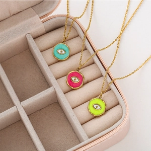Drei Gold-Edelstahlketten mit Evil Eye Anhängern in bunten Farben auf rosa Samt-Schmuckbox