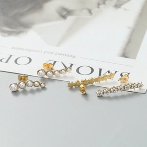 Détail macro de boucles d'oreilles fleur en or et clous en perles courbés sur magazine