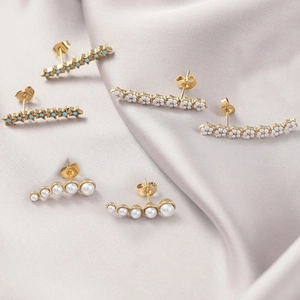 Lot de trois paires de boucles d'oreilles dorées et perles sur fond en soie de luxe
