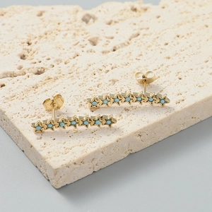 Détail de longues boucles d'oreilles étoiles dorées avec perles turquoise sur pierre