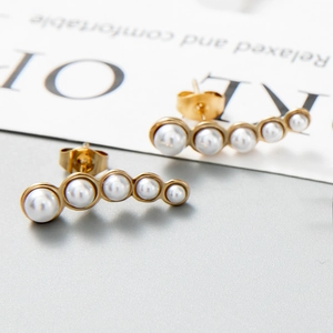 Détail macro de boucles d'oreilles dorées de style français avec perles blanches alignées