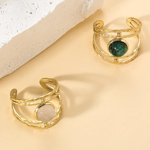 Macro shot of gold wide open rings with hammered texture and inlaid green and pink gemstones