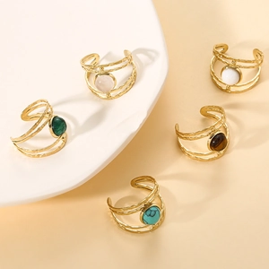 Detail of five stackable gold-plated ripple rings with colorful round gemstone inlays