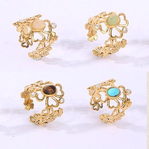 Detailed view of four open gold rings with colorful gemstones and hollow clover band design