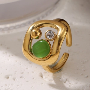 Détail macro d'une bague dorée avec pierre oeil de chat verte et diamant brillant