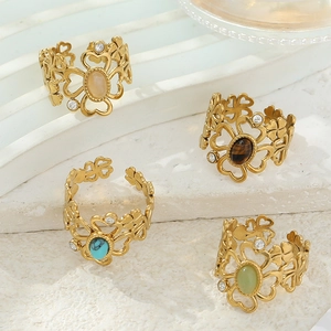 Bohemian gold flower rings set with cat-eye stones and diamonds on white stone steps
