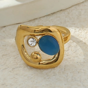Détail de la bague en acier doré avec pierre ovale bleue et cristal blanc brillant