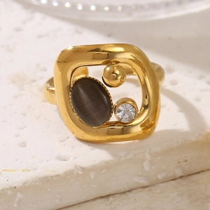 Détail d'une bague géométrique dorée avec pierre œil de chat grise et cristal clair