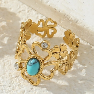 Detail of gold open ring with turquoise stone, hollow heart and clover design